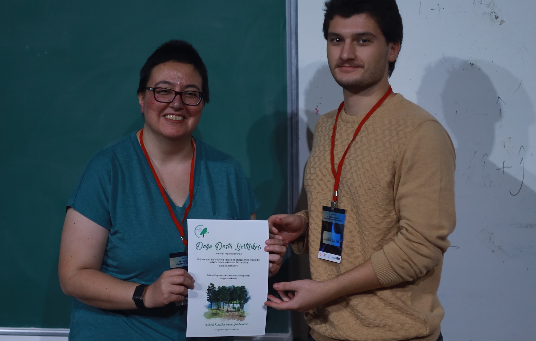 Seyfullah, for the organising team, hands over the speakers' gift: a certificate for two saplings planted in Hendek, Sakarya